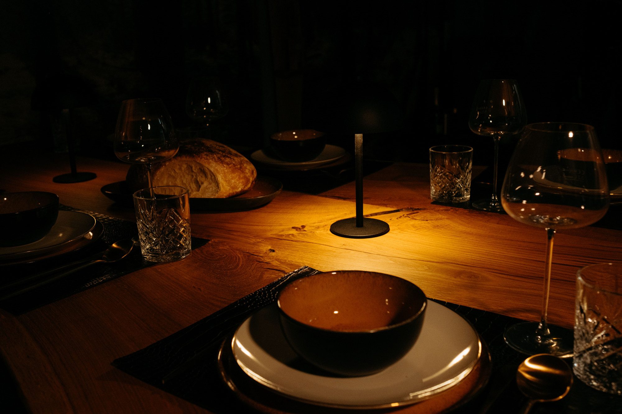Gedeckte Tafel auf einem Esstisch aus Eiche bei Kerzenlicht